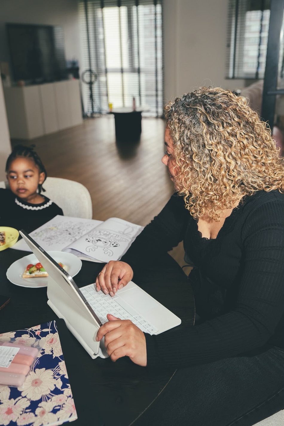 Shaïsta werkt aan tafel terwijl haar dochter erbij zit
